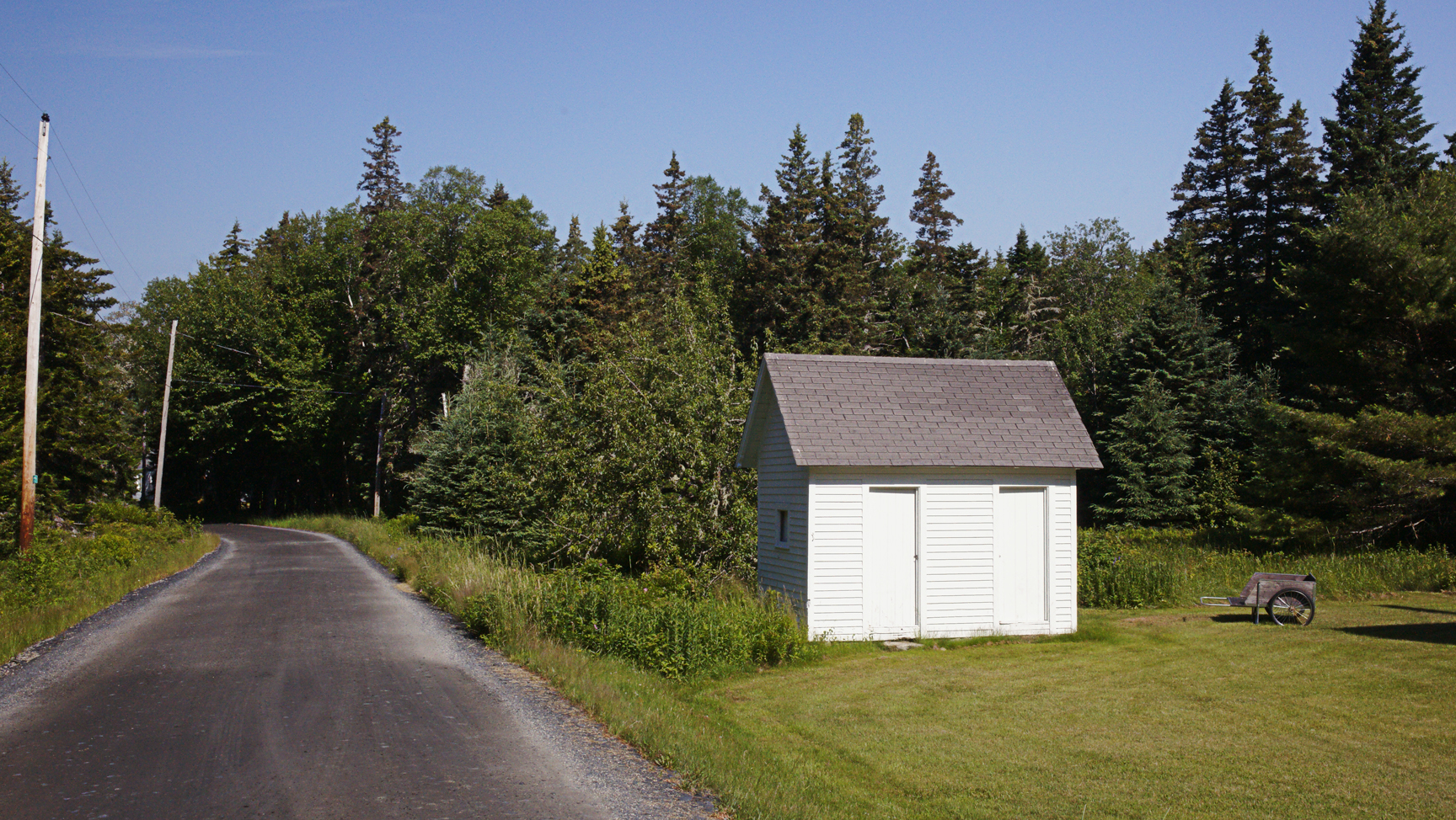 A white shed, and an empty road.