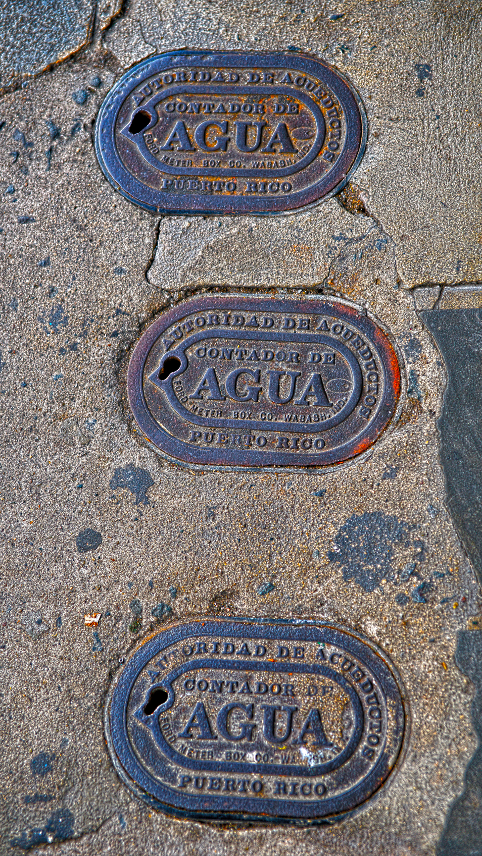 Agua/Water meter covers on the sidewalk.
